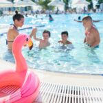 Children having fun and playing in an outdoor swimming pool on a bright summer day.