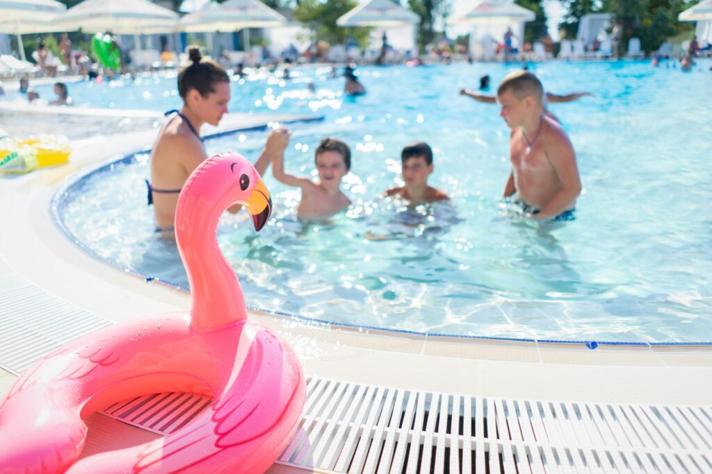 Children having fun and playing in an outdoor swimming pool on a bright summer day.