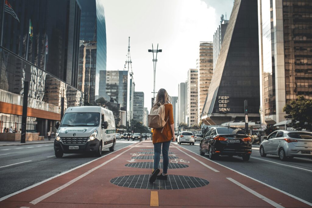 Woman walking in urban street surrounded by skyscrapers and modern architecture.