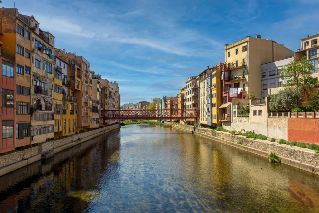 Vibrant view of the Onyar River with colorful buildings and Eiffel Bridge in Girona, Spain.