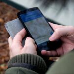 Close-up of hands using a map app on a smartphone outdoors, showcasing GPS navigation.