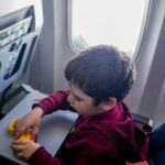 A young boy engrossed in playing with toy blocks on an airplane during a flight.