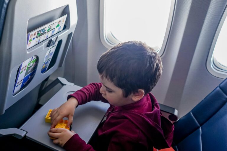 A young boy engrossed in playing with toy blocks on an airplane during a flight.