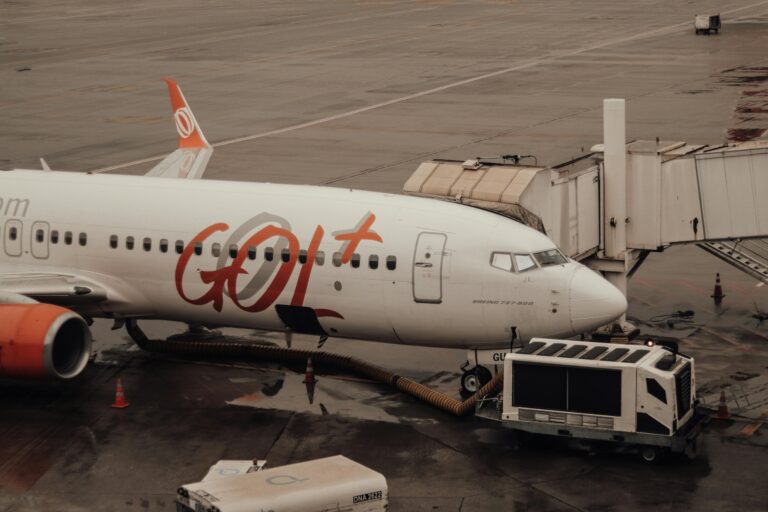 GOL Airlines aircraft connected to jet bridge at a wet airport terminal.